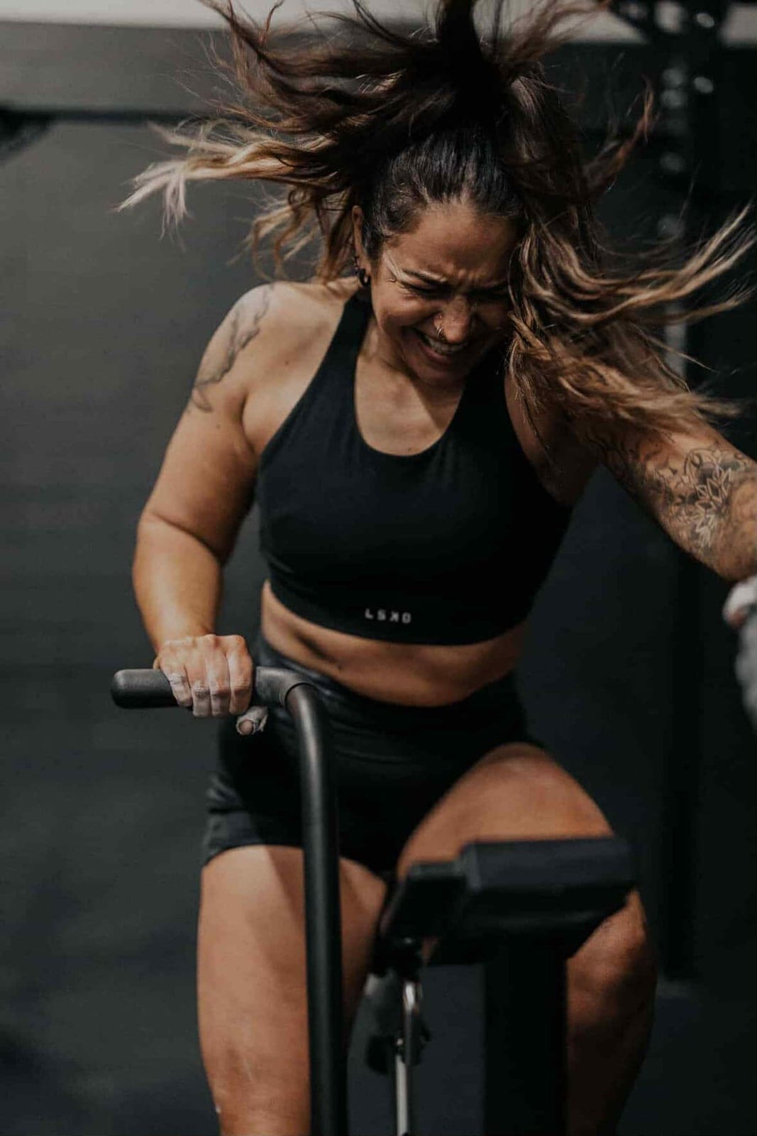 A member working hard on the air bike during a conditioning piece at House of Hybrid.