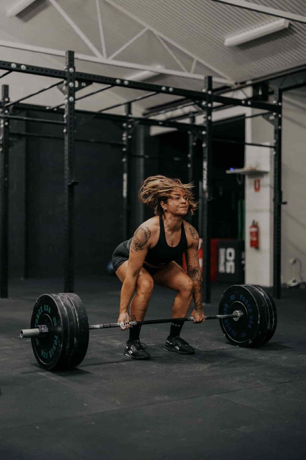 A member setting up for a deadlift under coach supervision at House of Hybrid.